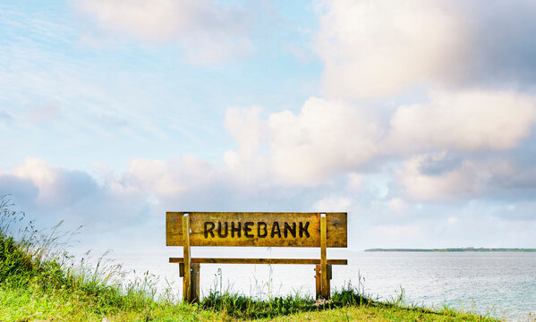 Holzbank an einem Ufer mit Blick zum Wasser