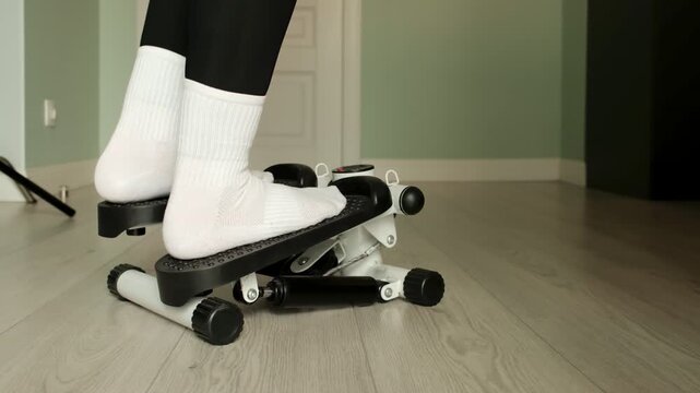 Person exercising on a mini stepper machine during a home cardio workout. Great footage for fitness motivation, healthy living, weight loss, and active lifestyle concepts.