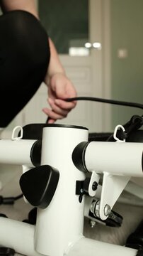 Close-up footage of attaching a resistance band to a mini stepper exercise machine. Demonstrates workout equipment setup for home fitness, strength training, and full-body exercise routines.