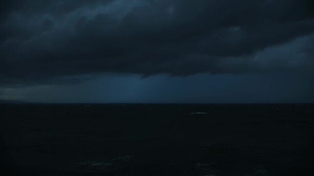 After bolt striking, shelf cloud producing lightning and lighting ocean at night, reflections