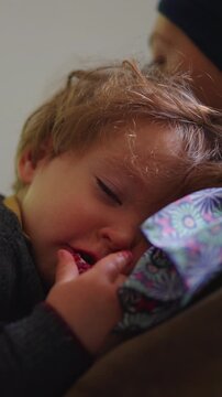 Young child resting peacefully in mother arms at home, nurturing family moment expressing attachment, comfort, trust, security and emotional connection