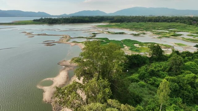 Aerial drone footage of a calm lake reflecting clouds and mountains at sunset light. Ideal for nature, travel, environment, wetland, and cinematic landscape projects.