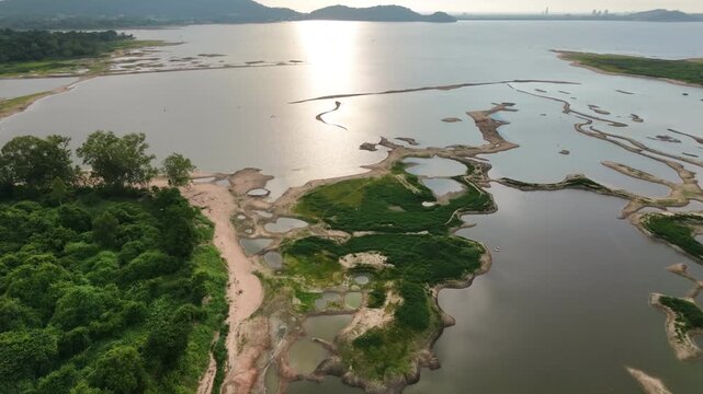 Aerial drone footage of a calm lake reflecting clouds and mountains at sunset light. Ideal for nature, travel, environment, wetland, and cinematic landscape projects.