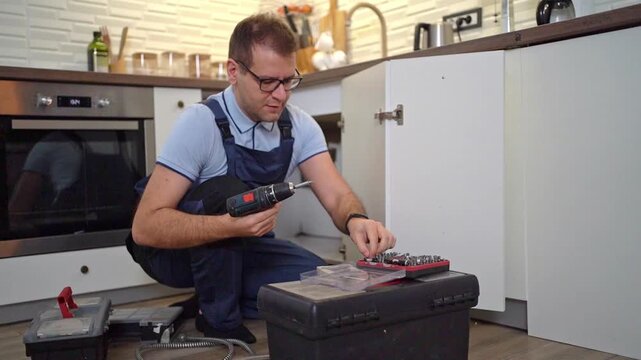 Young handyman fixing a kitchen cabinet hinge