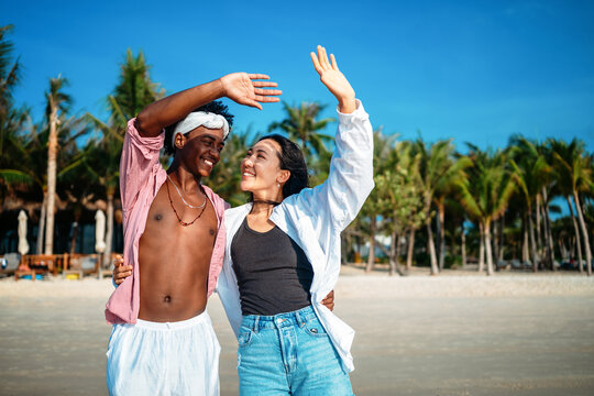 Happy couple having fun at the beach, playing and laughing together in a romantic tropical setting