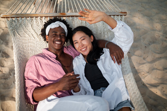 Happy interracial couple embracing and laughing at a scenic tropical beach resort on summer vacation