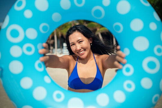 Cheerful woman posing with a blue swim ring on a sunny tropical beach