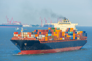 Fototapeta premium Container ship loaded with multicolored freight containers sailing near Shanghai port facilities. International maritime trade, global logistics, cargo transportation, import export operations