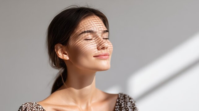 A serene woman with closed eyes basking in soft, glowing light and gentle shadows. Calm expression and radiant cheekbones evoke a tranquil spa and wellness mood.
