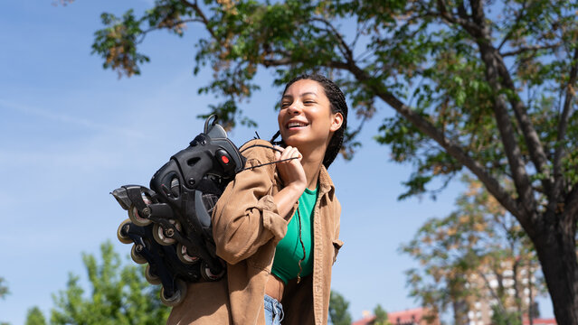 Young woman enjoying active lifestyle carrying rollerblades outdoors