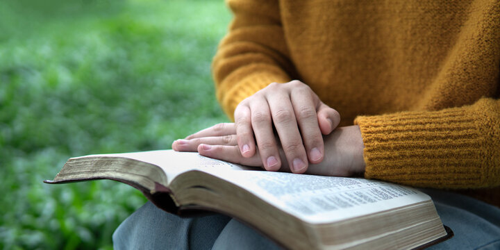 Peaceful hands resting on open Bible page for spiritual devotion.