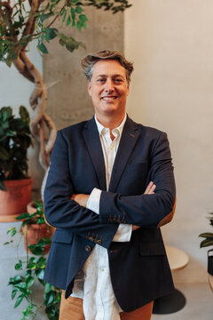 Confident businessman standing with arms crossed in modern office