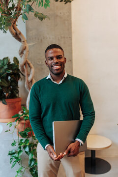 Smiling african american man holding laptop in office