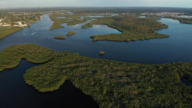 Mangrove islands line the winding Braden River as a small boat leaves a white wake near nearby suburban neighborhoods.