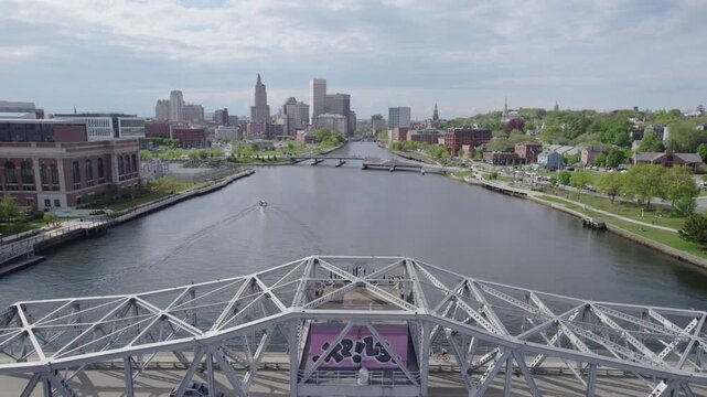 Slow aerial view over the Point Street Bridge in Providence Rhode Island with traffic, boat, and birds moving in the shot.