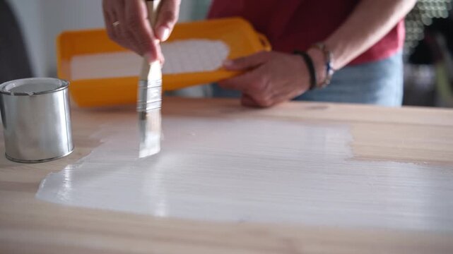 Woman Painting A Wooden Surface With A Brush During Home Renovation