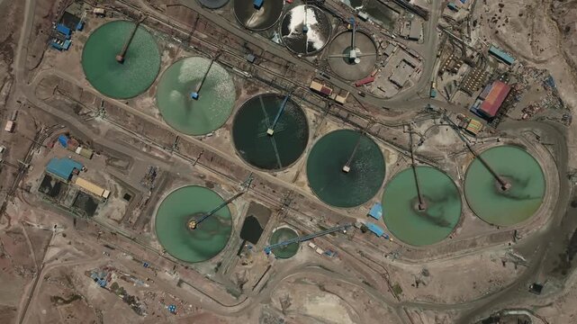 Aerial top view of multiple tailings thickeners working inside a large-scale copper mining complex. Circular tanks designed to separate solids and reclaim water for industrial reuse.