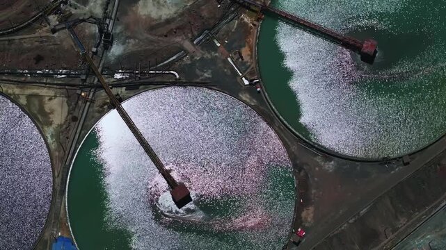 Professional drone footage featuring a smooth lateral pan over interconnected circular water recovery tanks within a major copper mining operation. The scene showcases industrial precision, environmen