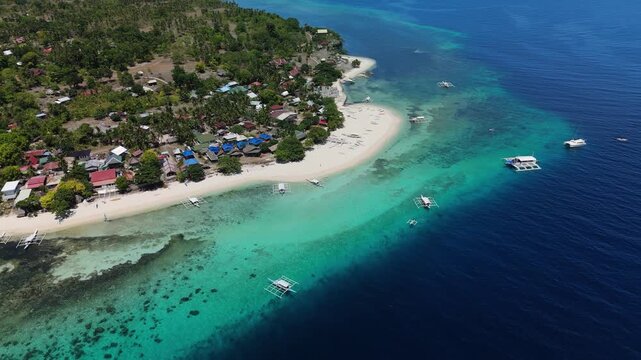 Drone pulls away from boats off Pamilacan Island, revealing white sand, reefs, village, and Bohol Sea