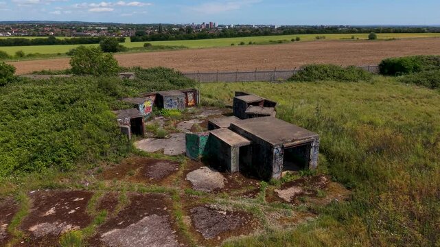 ZE1 gun emplacement ruins at Chadwell Heath seen from above as a drone ascends in orbit over octagonal concrete rooms, WW2 anti-aircraft battery remains in Essex, England.