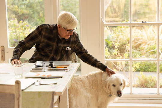 elderly man with his English cream golden retriever dog at home
