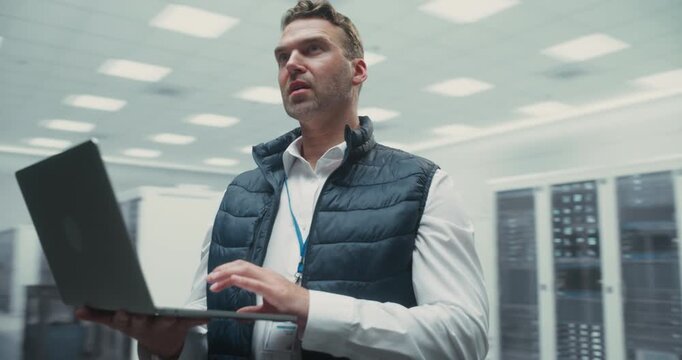 360 Degree. It Engineer Works on a Laptop Inside a Data Center, Analyzing AI Software and Server Diagnostics, Optimizing Cloud Network Infrastructure for Successful Operations. Arc Tracking Shot.