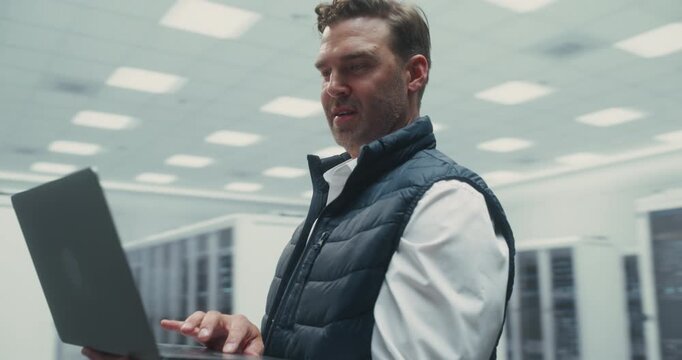 360 Degree. Specialist Uses Laptop Among Server Racks, Configuring AI Algorithms and Monitoring Cloud Network Performance to Optimize Digital Infrastructure for Successful Data Center. Tracking Shot.