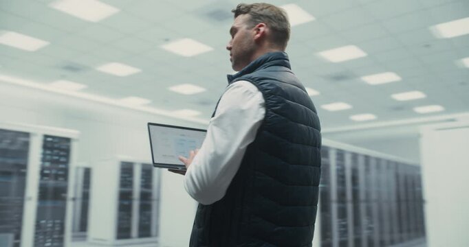 360 Degree. Specialist Uses Laptop in Data Center, Working With AI Technology to Optimize Cloud Systems and Improve Server Performance for Digital Operations. Orbital Cinematic Arc Tracking Shot.