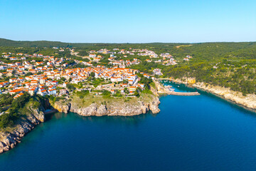 Obraz premium Aerial panoramic view of Vrbnik historic town and harbor on Krk Island, Croatia. Red-tiled roofs, rocky cliffs, and turquoise Adriatic waters create a stunning Mediterranean seascape