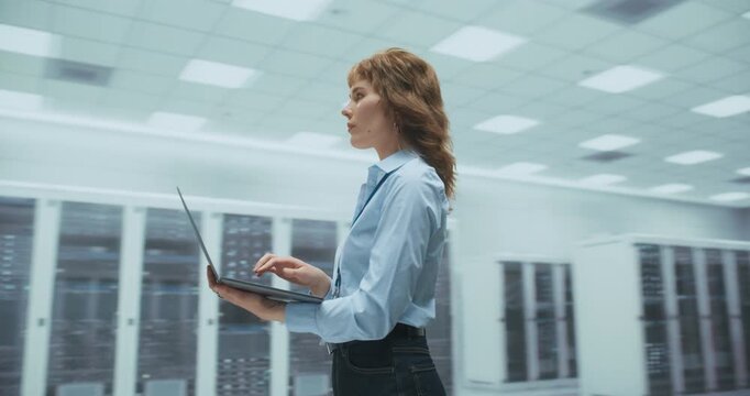 360 Degree. Female Engineer Uses Laptop to Manage AI Network Infrastructure Among Server Racks in a Data Center, Analyzing Cloud Performance and Optimizing System. Cinematic Arc Tracking Shot.