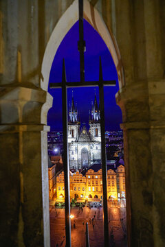 Aerial view of the illuminated Church of Our Lady before Tyn rising above the historic Old Town Square at night, framed by a stone archway in Prague, Prague, Czechia.