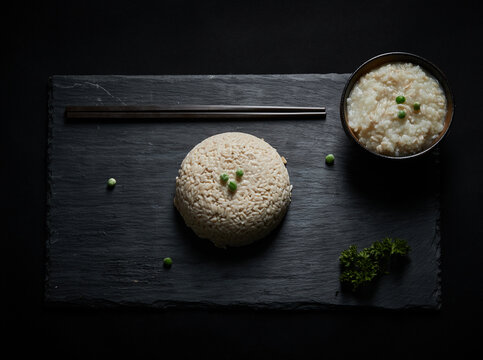 Oat groats and steamed oat rice laid out on a black bluestone slab