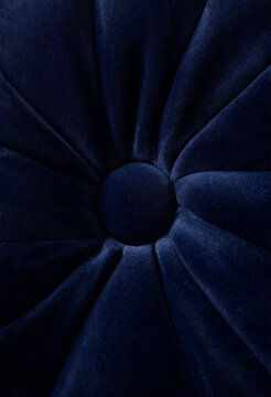 Navy velvet tufted upholstery cushion with radial pleats and central button in deep blue tones. Home decor textile accent.