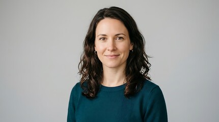 Fototapeta premium Professional portrait of a confident smiling mid adult brunette woman in a teal sweater, isolated on a clean grey background