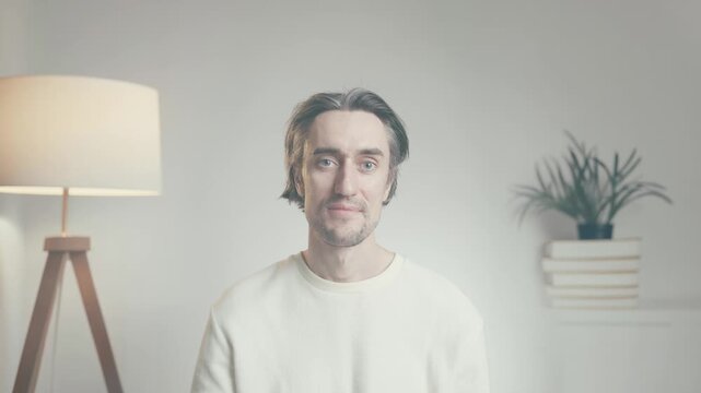 Young man looking uncertain indoors, confused expression in minimalist interior