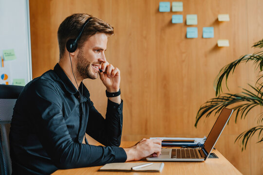 Businessman using laptop and headset in modern office, professional employee working remotely during online meeting, corporate communication, customer support, digital workspace business technology