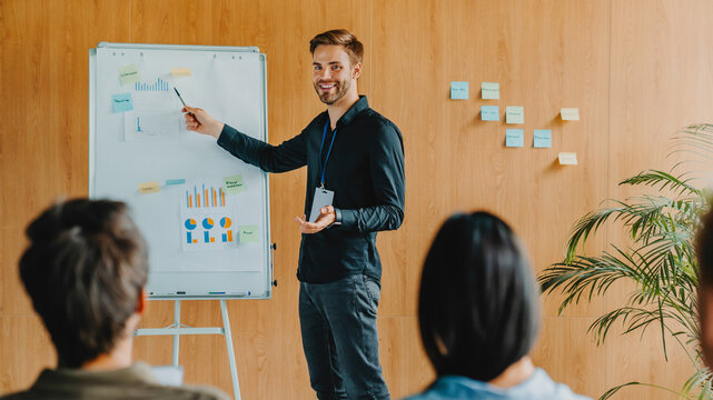 Professional businessman leading presentation at corporate seminar while discussing project with colleagues, business training session, teamwork, leadership and company strategy planning concept