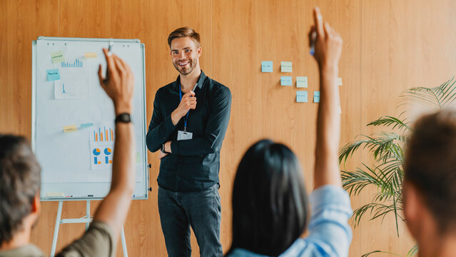 Young businessman presenting business project to group of employees during corporate training, office seminar, professional coaching, teamwork collaboration and leadership development concept