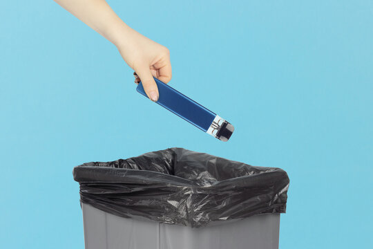 throw the electronic cigarette into the trash, outstretched hand with electronic cigarette in front of the trash can, concept of harm from electronic cigarettes
