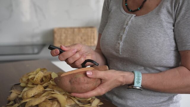 Girl Peeling Raw Sweet Potatoes With Potato Peeler in Kitchen