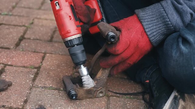 Removing corrosion from brake caliper pad contact surfaces with rotary wire brush. Brake bracket preparation improving pad clip fit and movement. DIY automotive repair restoring clean caliper mounting