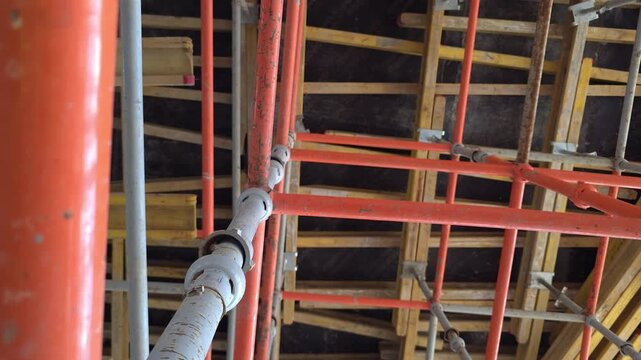 Moscow, June 20 2026, Overhead view of construction scaffolding with red and yellow pipes. Close-up shows a red pipe with a white clamp. Sturdy framework supports building projects. Ideal for architec