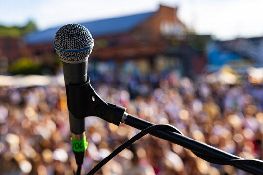 rofessional vocal microphone close up on live concert stage with blurred crowd background