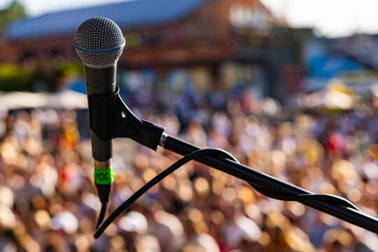 rofessional vocal microphone close up on live concert stage with blurred crowd background