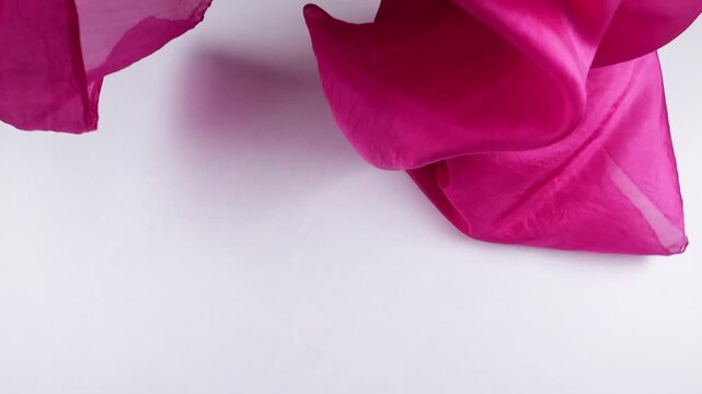 Pastel pink silk fabric falls in slow motion against a white background. Elegant textile creates smooth movements and natural drapery for luxury fashion, apparel commercials, and cosmetic branding.