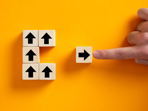 A finger forces a wooden block back into alignment with the group, symbolizing social pressure, corporate rules, and suppressing deviation.