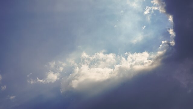 Sunlight breaking through clouds in a bright blue sky.