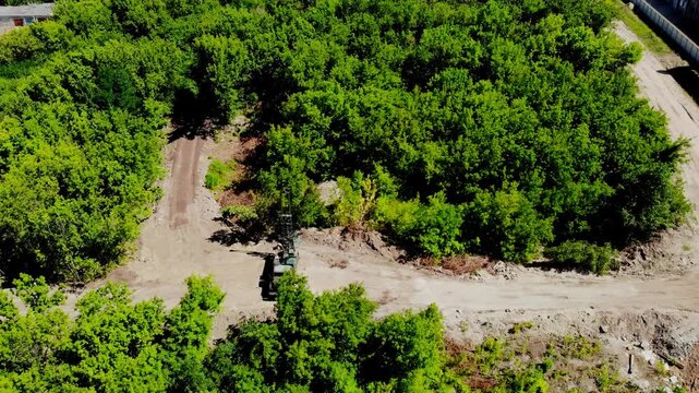 Aerial drone view of a mobile geotechnical drilling rig conducting soil investigation and ground sampling at a future construction site near a forested area in Sumy, Ukraine. The specialized drilling 