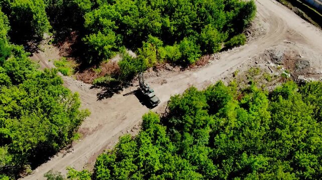Aerial drone view of a mobile geotechnical drilling rig conducting soil investigation and ground sampling at a future construction site near a forested area in Sumy, Ukraine. The specialized drilling 