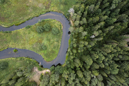 Aerial view of the winding river in Lahemaa National Park, surrounded by lush green forests and meadows in Lahemaa, Estonia.
